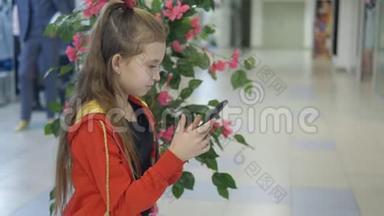 在购物中心坐着玩智能手机的女<strong>孩子</strong>。 宝宝在等父母去购物